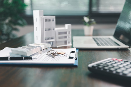 House model placed on table alongside coins, paperwork symbolizes real estate investment, property valuation, representing financial planning, mortgage options, market analysis in property business.の写真素材