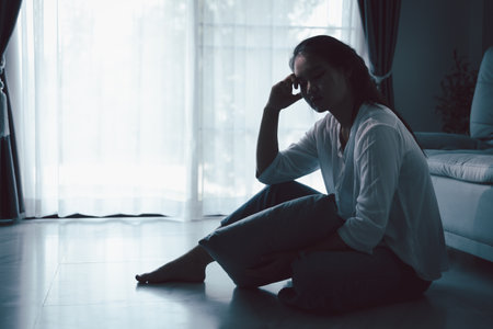 Tired depressed desperate tired girl sadly sitting on couch at home. Young woman is sitting on floor living room, feeling sad and depressed. Psychological problem. Depression and loneliness concept.の写真素材