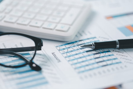 Close up of financial report with pen, calculator and eyeglasses on office desk. Concept of...