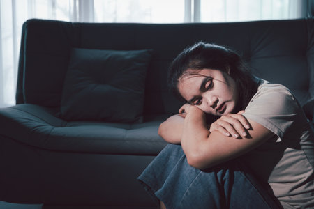 Sorrowful woman sat alone, overwhelmed by emotion, her sad and unhappy expression revealing deep despair, stress and distress left feeling depressed. sorrowful sad, despair alone, depressed stressの写真素材