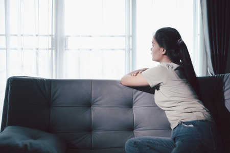 Sorrowful woman sat alone, overwhelmed by emotion, her sad and unhappy expression revealing deep despair, stress and distress left feeling depressed. sorrowful sad, despair alone, depressed stressの写真素材