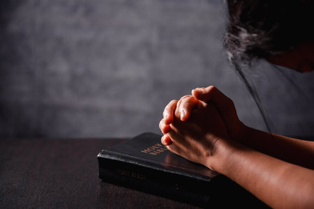 Bible in hand, christian lifts prayer in worship, holding firmly to holy concept of faith, hope and deep belief guides their spiritual life. Hands together in prayer to God along with bibleの写真素材