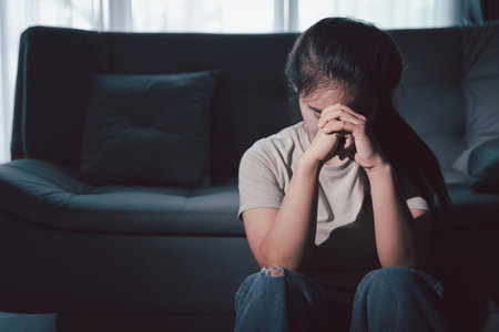 Sorrowful woman sat alone, overwhelmed by emotion, her sad and unhappy expression revealing deep despair, stress and distress left feeling depressed. sorrowful sad, despair alone, depressed stressの写真素材