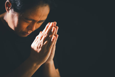 Dark silence of the church, a Christian lifts their hand in prayer to God, a symbol of worship, faith, and hope-embracing the spiritual concept of religion and believing in Jesus Christ.の写真素材