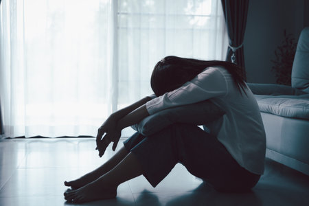 Tired depressed desperate tired girl sadly sitting on couch at home. Young woman is sitting on floor living room, feeling sad and depressed. Psychological problem. Depression and loneliness concept.の写真素材
