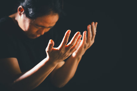 Dark silence, a person lifts their hand in prayer, a symbol of worship, faith, and hope-embracing the spiritual concept of religion.の写真素材