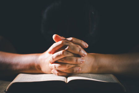 Hands clasped in prayer over the holy Bible, the faithful Christian worships God in church, holding onto hope and belief, guided by religion and a deep commitment to their religious faith.の写真素材