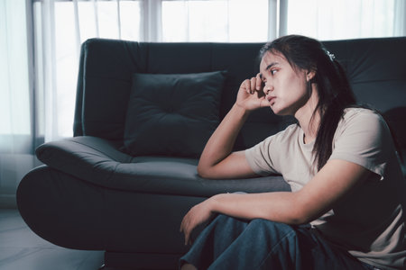 Sorrowful woman sat alone, overwhelmed by emotion, her sad and unhappy expression revealing deep despair, stress and distress left feeling depressed. sorrowful sad, despair alone, depressed stressの写真素材