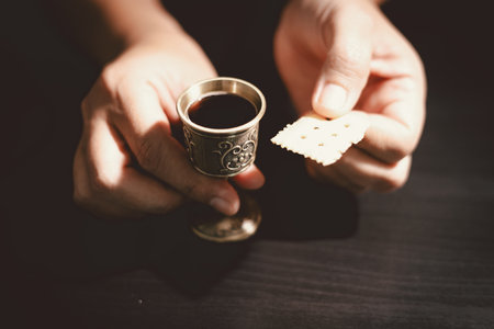 Hands holding communion bread with a wooden bowl and wine cup, symbolizing Holy Communion, the Eucharist, the sacrifice of Jesus Christ and Christian faith in the Lord Supper.の写真素材
