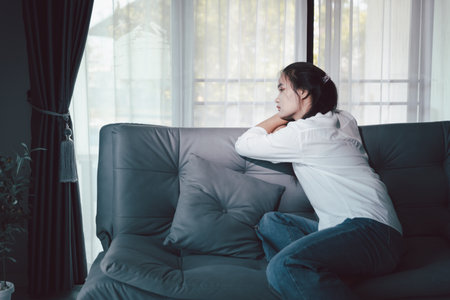 Sorrowful woman sat alone, overwhelmed by emotion, her sad and unhappy expression revealing deep despair, stress and distress left feeling depressed. sorrowful sad, despair alone, depressed stressの写真素材