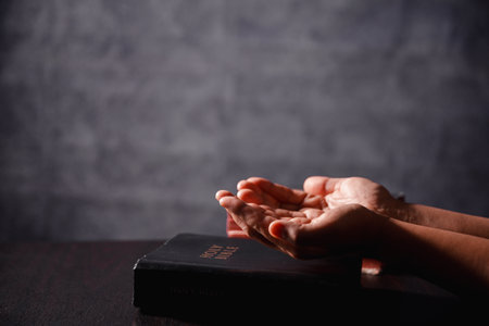 Bible in hand, christian lifts prayer in worship, holding firmly to holy concept of faith, hope and deep belief guides their spiritual life. Hands together in prayer to God along with bibleの写真素材