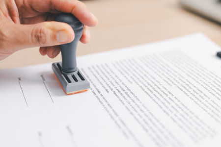 Businessperson stamping document on clipboard at office desk, concept of contract approval, legal authorization, business agreement validation or administrative paperwork process. stamp approval.の写真素材