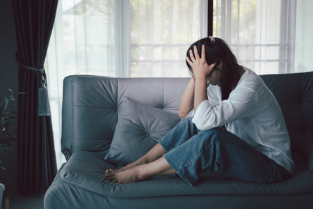 Sorrowful woman sat alone, overwhelmed by emotion, her sad and unhappy expression revealing deep despair, stress and distress left feeling depressed. sorrowful sad, despair alone, depressed stressの写真素材