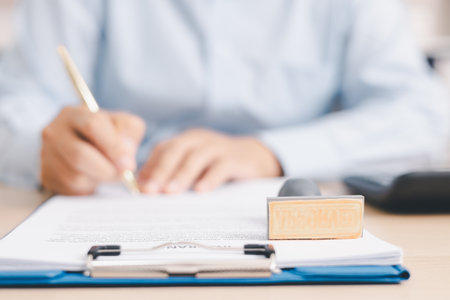 Businessperson stamping document on clipboard at office desk, concept of contract approval, legal authorization, business agreement validation or administrative paperwork process. stamp approval.の写真素材