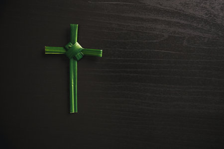 Palm leaf cross attached to crown of thorns green palm leaves on dark background symbolizing Christian faith Palm Sunday sacrifice Easter reflection religious concept for worship prayer church designの写真素材