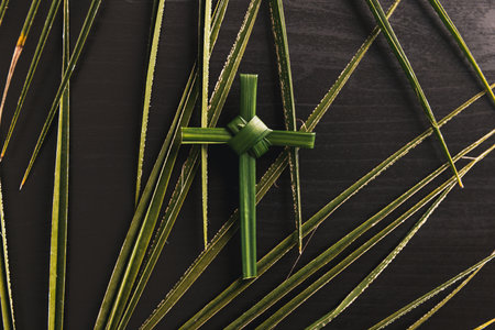 Palm leaf cross attached to crown of thorns green palm leaves on dark background symbolizing Christian faith Palm Sunday sacrifice Easter reflection religious concept for worship prayer church designの写真素材