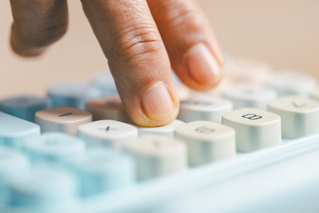 Close-up of a hand pressing calculator keys for budgeting, accounting and financial analysis. Business expense planning, tax calculation, office desk background, copy space for paperwork.の写真素材