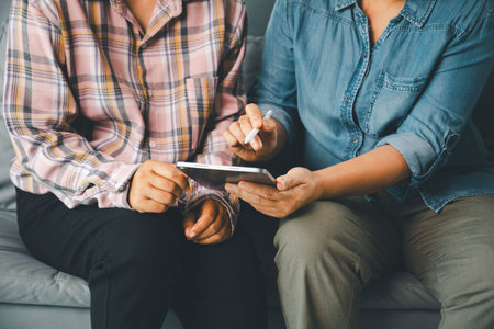 Therapist guides female client using digital tablet during counseling consultation, showing mental health support, assessment, professional care, communication, trust, and wellness planning indoors.
