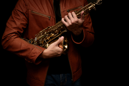 musician saxophone player holding his saxophone on isolated black background.の写真素材