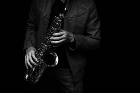 male jazz saxophone player on the stage with leather jacket black and white colorの写真素材