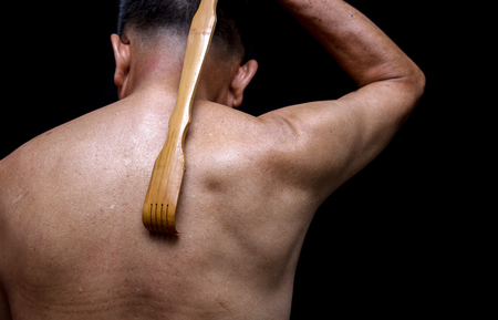 close up of back scratching oldman with his long handle bamboo stick back scratcher.の写真素材