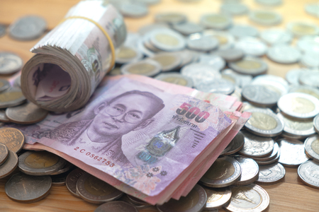 thai baht currency saving banknote and coins on wood table.の写真素材