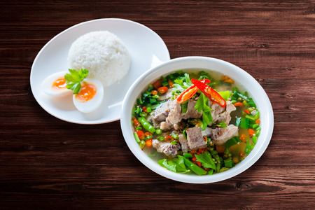 Spicy Pork with Pork bone Soup with Rice and Egg on the Wood Table, Leng soup in Thai word.の写真素材