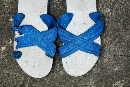 Old Unused Rubber Sandal with Tear and Torn on the Outdoor Concrete Floor.