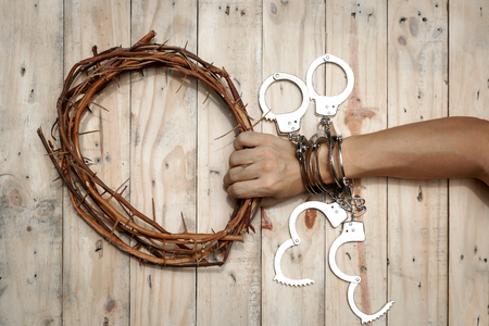 Man Holding Jesus Crown Thorns with His Hand and Many Handcuffs. Concept Picture of a Trapped Man Who Need Help by Jesus the Savior.の写真素材