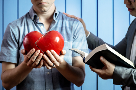 Concept Picture of a Caucasian Man with His Broken Heart and Healing from the Words of God by Pastor.の写真素材