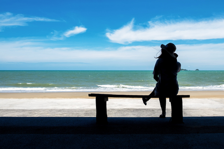 Silhouette Picture of a Woman Relaxing on the Wood Bench Near the Beach.の写真素材