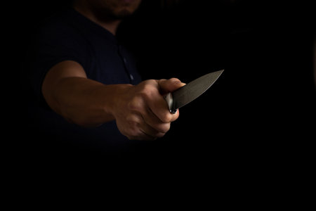 Adult Man Holding Sharp Knife in the Shadow. Concept Picture of Murderer, Killer, Assasin, Robber or Theft.の写真素材