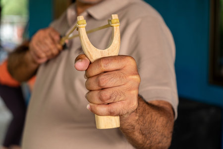 A Man is Aiming and Getting Ready to Shoot a Pebble from the Slingshot in His Hands.
