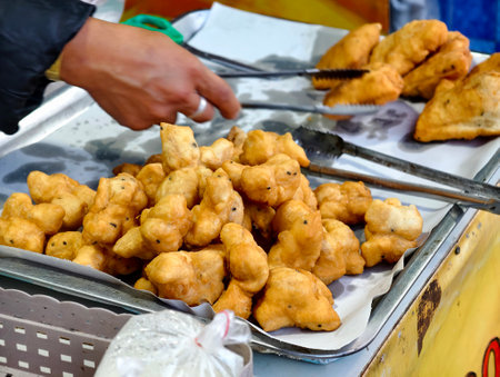 A vendor is placing freshly fried Chinese crullers into a bag to sell to a customer.の写真素材