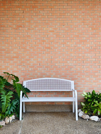 A clean white metal bench is placed in front of the brick-walled building for relaxation.