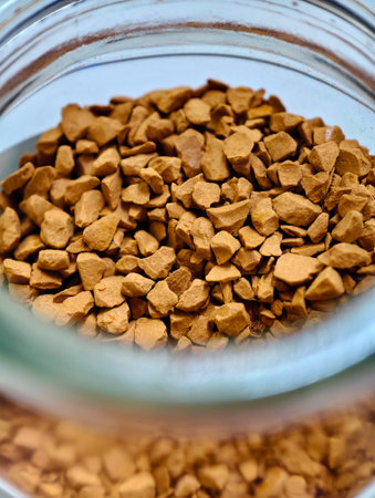 Macro shot of freeze-dried instant coffee granules stored in a transparent glass jar. Rich brown texture and natural tones make this image ideal for food and beverage branding, kitchen content, blogs, cafes, packaging, or advertising coffee products.の写真素材
