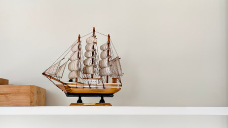 Decorative wooden sailing ship model with canvas sails displayed on a white shelf. Perfect for...