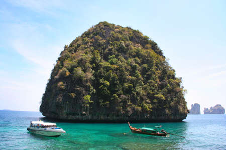island with green trees, blue sea water and boatsの写真素材