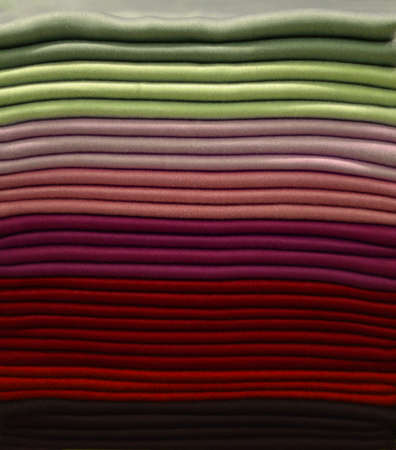 Stack of colorful t-shirts. Layers of colorful fabric. Stack of colorful folded clothes, multicolored background. Pile of bright folded clothesの写真素材