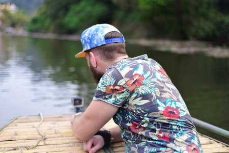 Young man guy in casual t-shirt and cap posing on nature background. Traveling lifestyle concept....