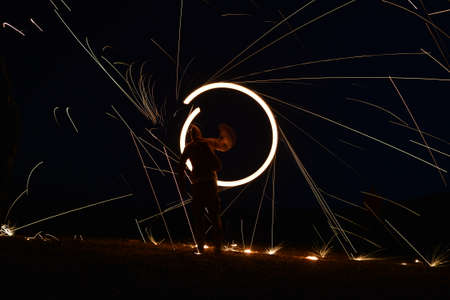 Iron wool circle drawing light fireworks. Burning Steel Wool spinning, Trajectories of burning sparks at night. Movement light effect, steel wool fire hoop. long exposure light painting, Pyrotechnicの写真素材