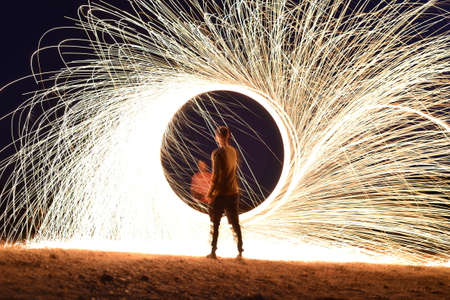 Iron wool circle drawing light fireworks. Burning Steel Wool spinning, Trajectories of burning sparks at night. Movement light effect, steel wool fire hoop. long exposure light painting, Pyrotechnicの写真素材
