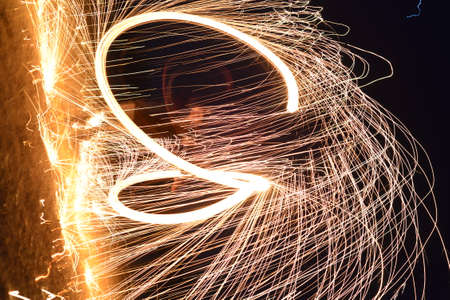 Iron wool circle drawing light fireworks. Burning Steel Wool spinning, Trajectories of burning sparks at night. Movement light effect, steel wool fire hoop. long exposure light painting, Pyrotechnicの写真素材