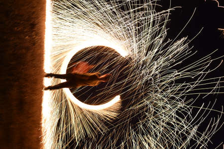 Iron wool circle drawing light fireworks. Burning Steel Wool spinning, Trajectories of burning sparks at night. Movement light effect, steel wool fire hoop. long exposure light painting, Pyrotechnicの写真素材