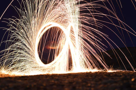 Iron wool circle drawing light fireworks. Burning Steel Wool spinning, Trajectories of burning sparks at night. Movement light effect, steel wool fire hoop. long exposure light painting, Pyrotechnicの写真素材