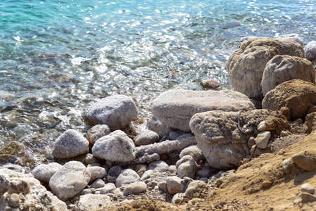 View of Dead Sea coastline. Salt crystals at sunset. Texture of Dead sea. Salty sea shore. Landscape Dead Sea coastline with natural relief channels in summer day,  failures of the soilの写真素材
