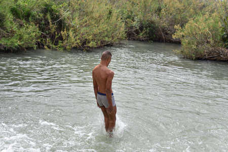 Man jumping with joy by a lake. Cliff Jumping into the river water, Summer Fun Lifestyle. Healthy, fit and muscular man jumping for joy on a beachの写真素材