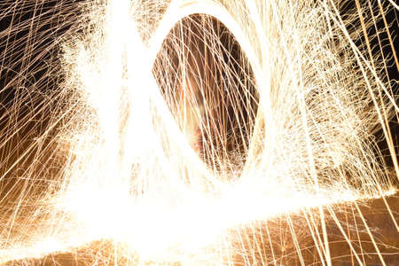 Sparks from spinning steel wool at night, close-up