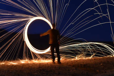 Man with burning steel wool at night, closeup. Sparks of fireの写真素材