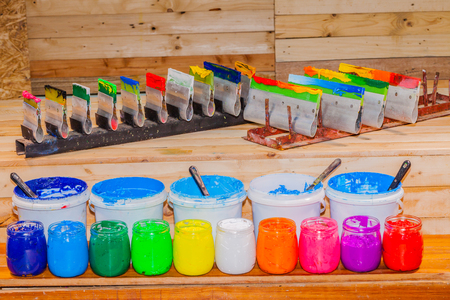 colorful of Plastisol Ink in the clear glass can on the pinewood table for screen print tee shirt. Plastisol ink useful in tee shirt factory and in industry for exportの写真素材